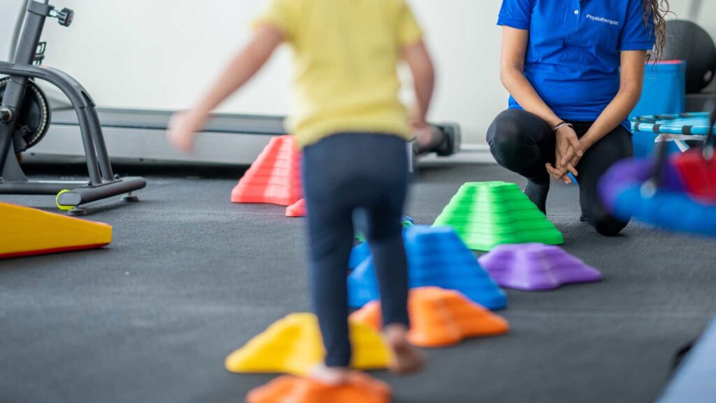 A young child falls on the grass near a lake, illustrating the importance of developing balance, coordination, and motor skills. Paediatric physiotherapy helps children improve stability, prevent falls, and build confidence in movement through targeted therapy sessions.