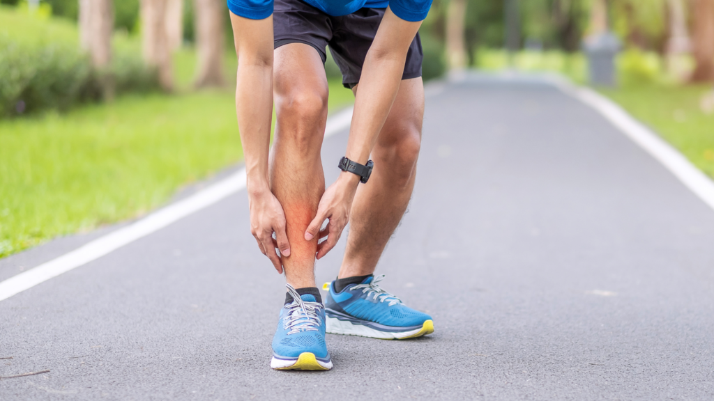  A runner gripping their shin in pain, indicating possible shin splints or a sports injury. Proper physiotherapy, stretching, and supportive footwear can aid recovery and prevent further strain.