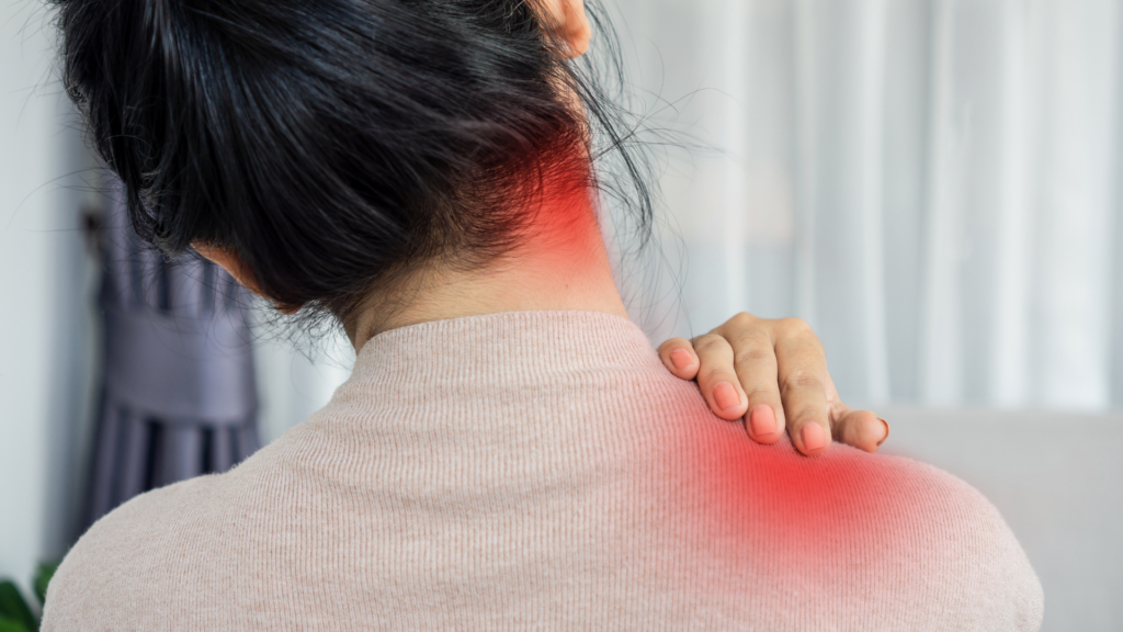 A woman holding her neck and shoulder in discomfort, highlighting pain and tension. Physiotherapy and posture correction can help alleviate chronic neck pain and stiffness.