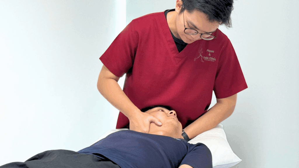 Physiotherapist at Physio & Sole Clinic performing TMJ manual release on male patient