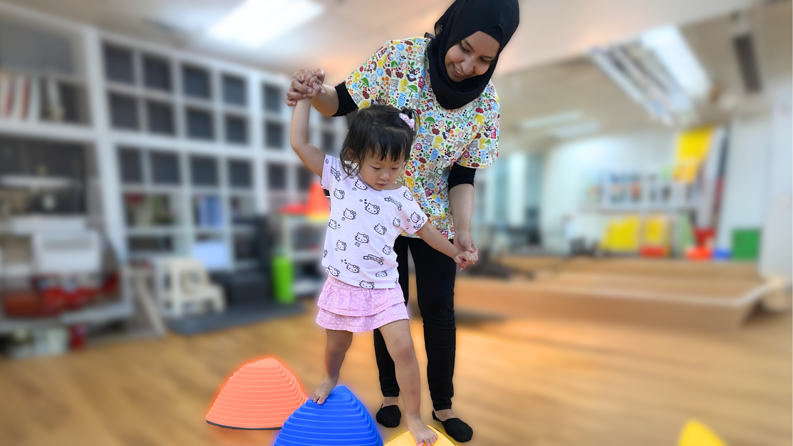 Paediatric physiotherapist helping a child navigate balance equipment during a gait and motor skills assessment in Singapore.