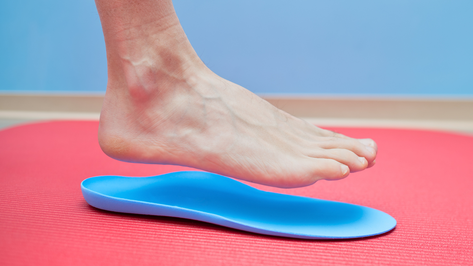 Close-up of a foot about to step into a blue custom orthotic for arch and knee support.