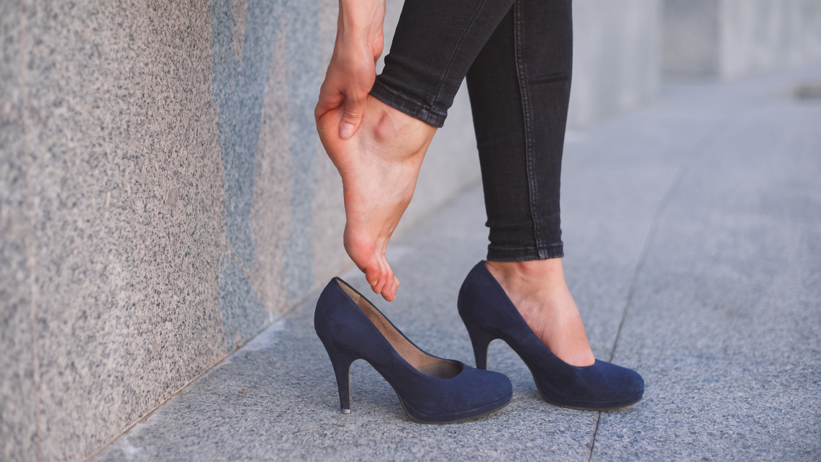 Woman experiencing foot pain in Singapore from prolonged high heel use.
