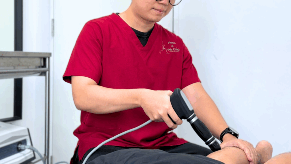 Podiatrist from Physio & Sole Clinic applying shockwave therapy to a patient’s leg during treatment.