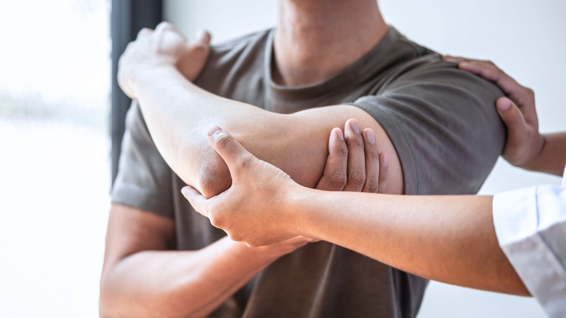 A physiotherapist assessing a patient’s shoulder mobility during a physical examination in a clinic.