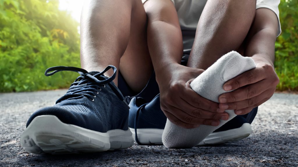 Person removing shoes after exercise due to tight shoes, illustrating a common cause where nail fungus can develop.
