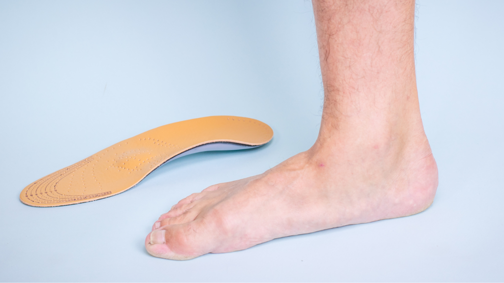 Bare foot positioned beside an orthotic insole, representing assessment and support for foot posture and arch alignment.