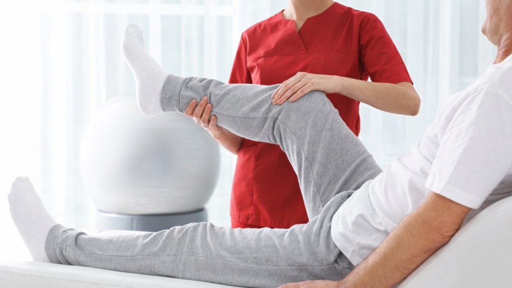 Physiotherapist assisting a patient with a knee mobility exercise during a physiotherapy session.
