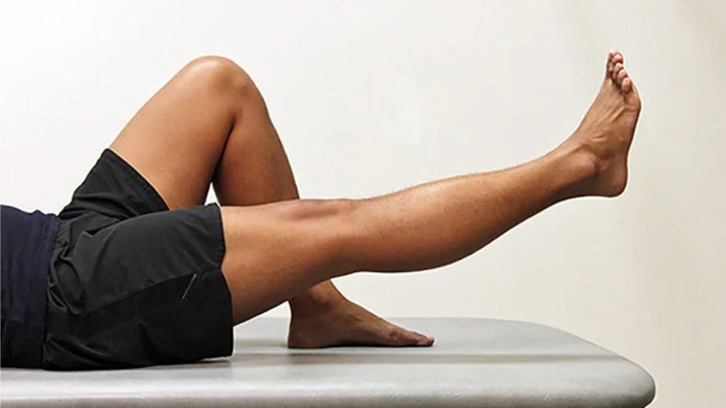 Person performing a straight leg raise exercise to strengthen the knee.
