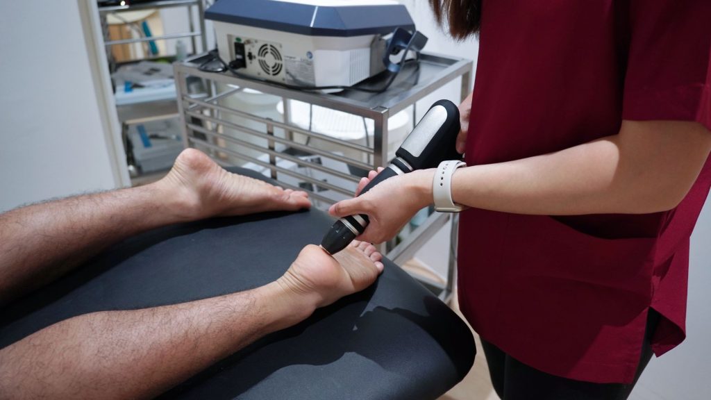 Physiotherapist applying shockwave treatment to the foot to stimulate healing in chronically irritated tendon tissue