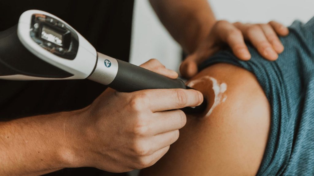 Physiotherapist applying shockwave therapy to the shoulder to stimulate tendon healing and reduce pain