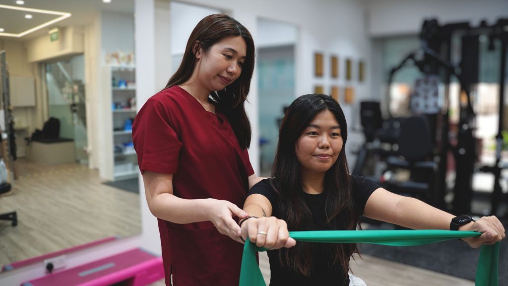 Physiotherapist guiding a patient through resistance band exercises as part of a personalised rehabilitation programme