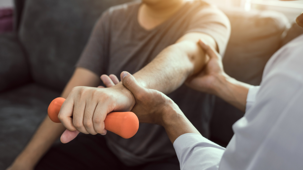 Physiotherapist assisting a patient with wrist and forearm strengthening exercise using a hand weight to support elbow recovery