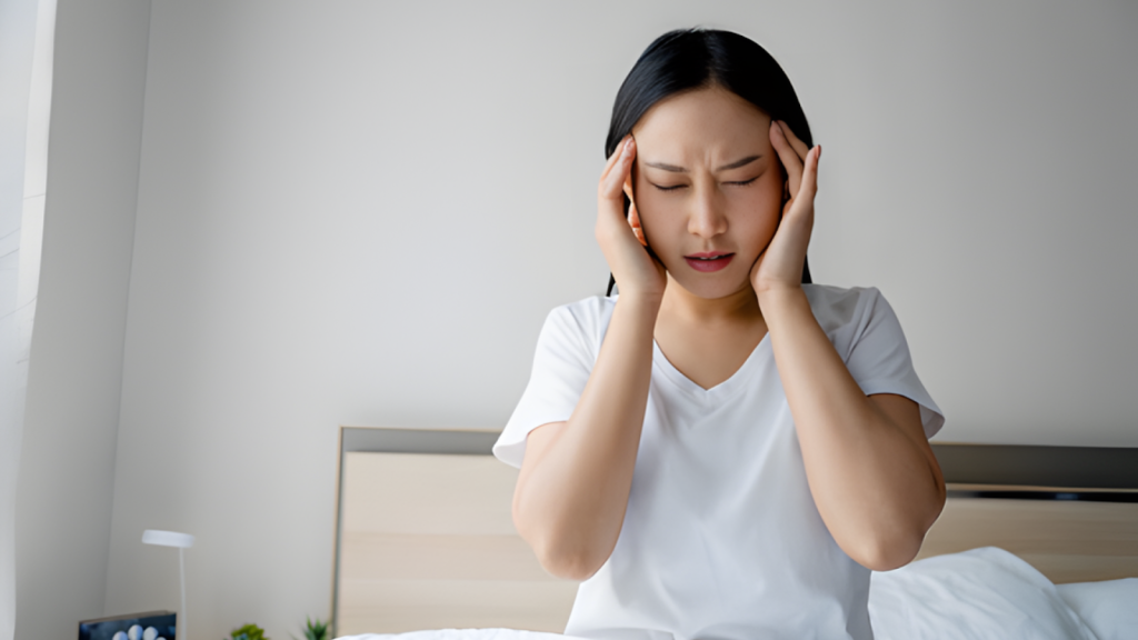Woman holding her temples experiencing a tension headache, illustrating chronic tension headaches linked to stress or neck strain