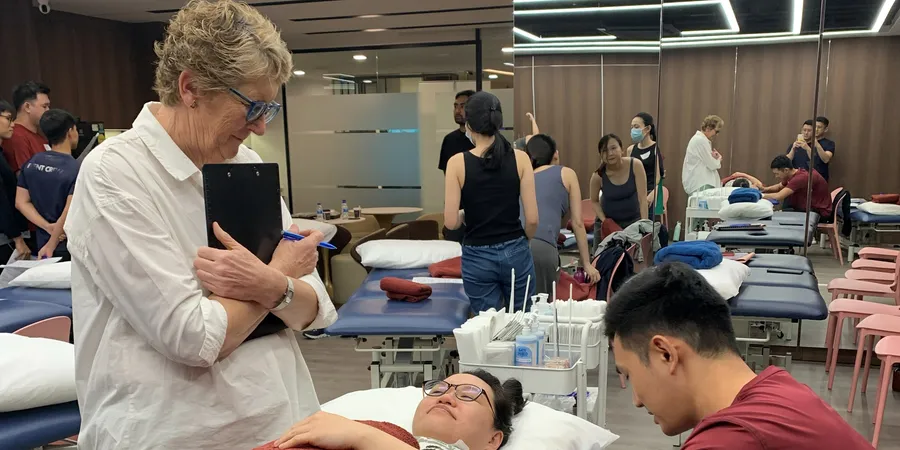 An instructor watching a physio practise a hands-on technique