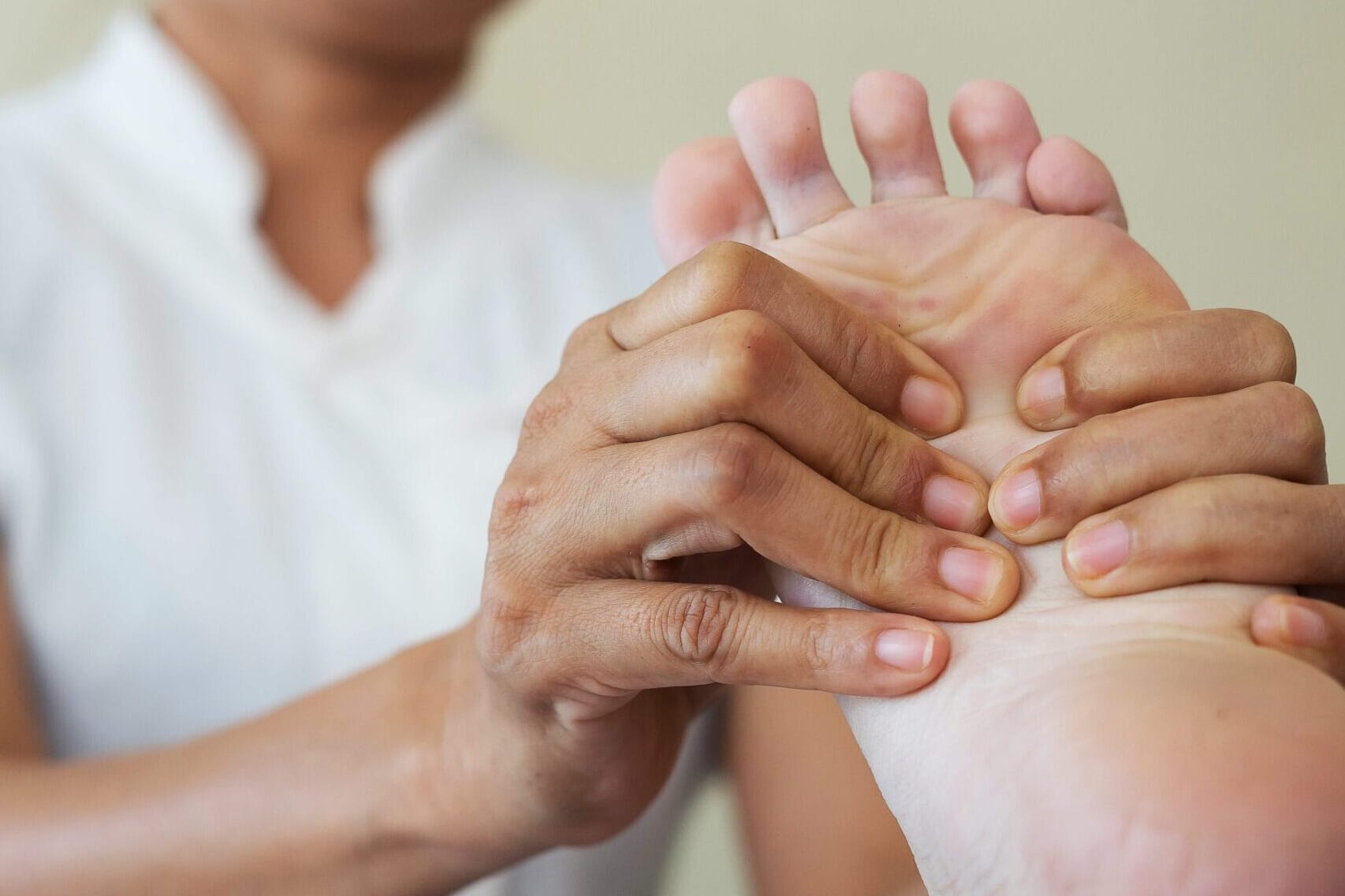 Podiatrist pressing the ball of a patient's foot to assess forefoot pain
