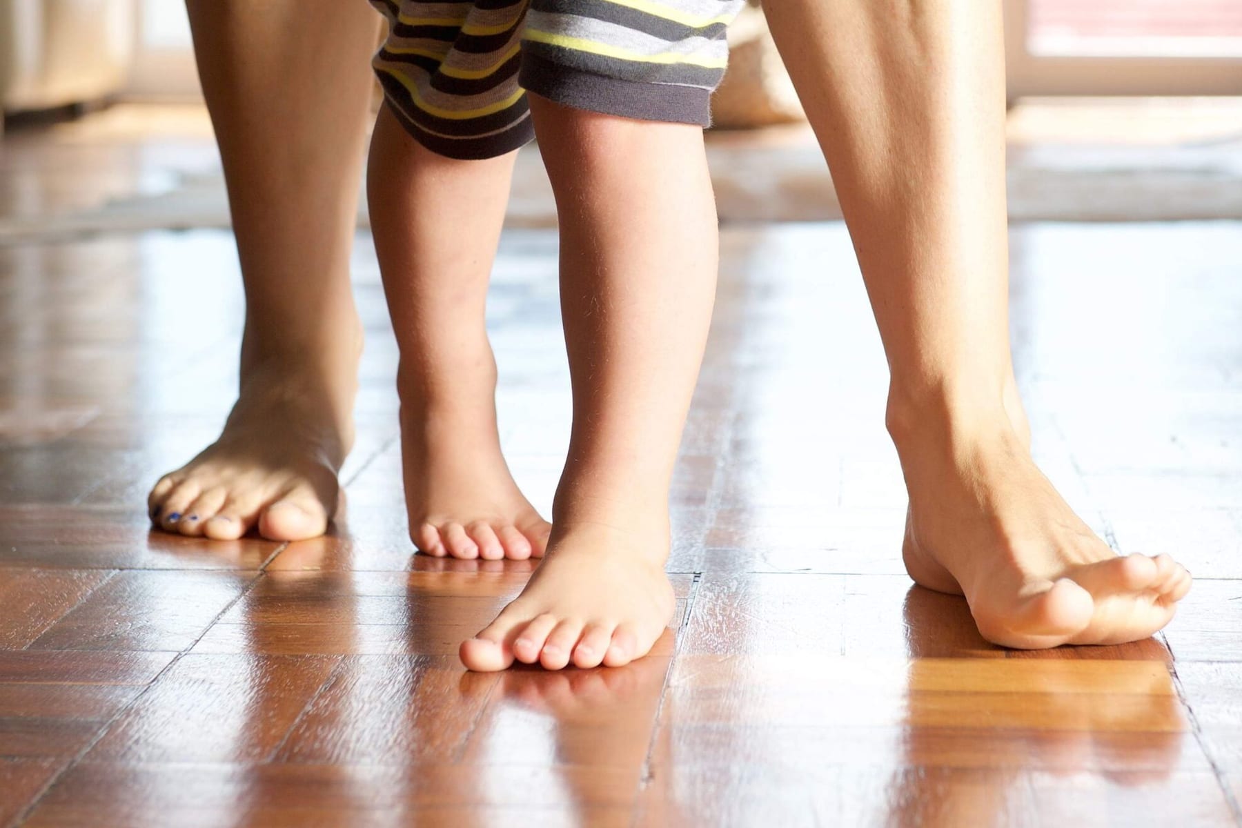 Toddler standing with the feet turned inwards while an adult steadies them