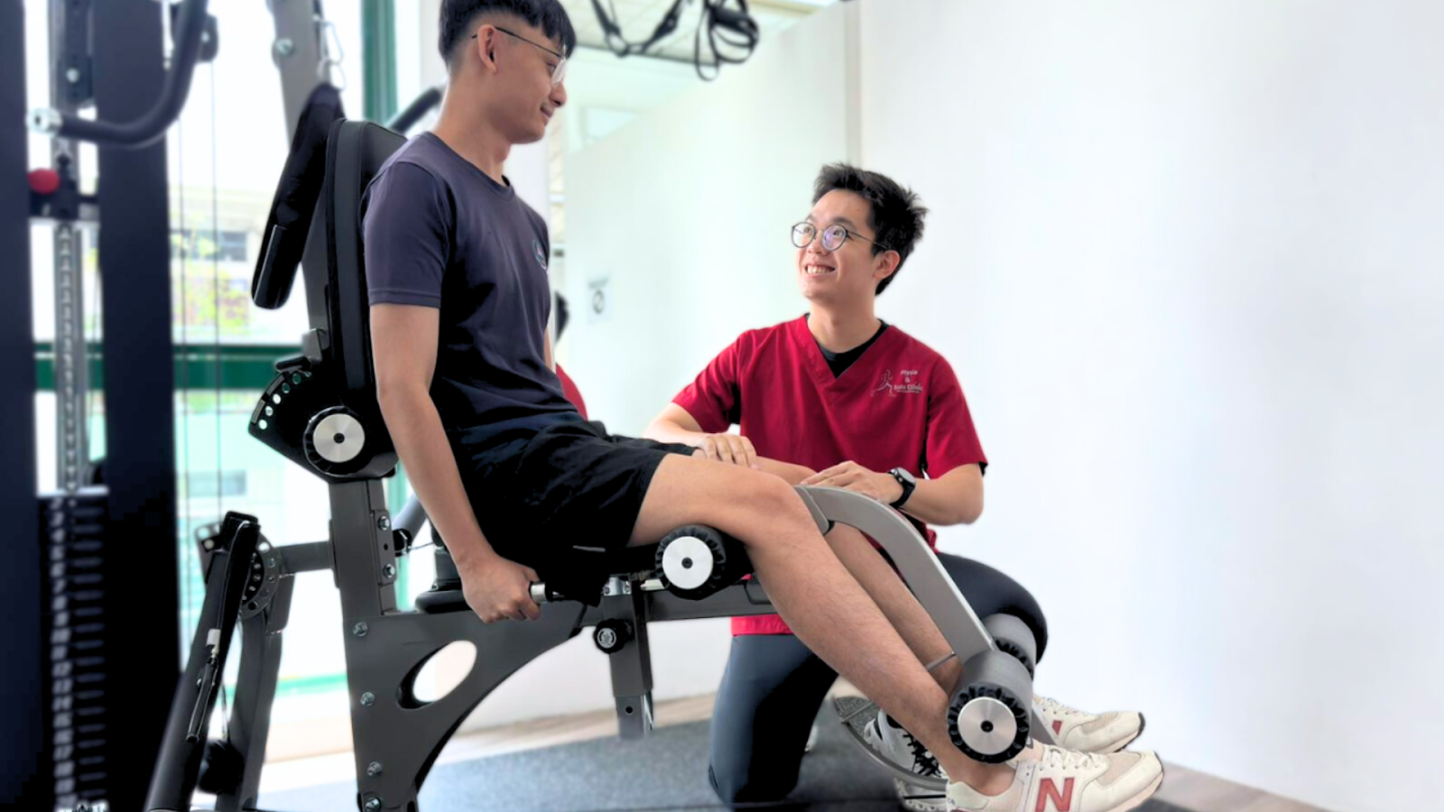 Sports physiotherapist supervising a patient using gym-strengthening equipment in a clinic, emphasising structured rehabilitation and recovery training.