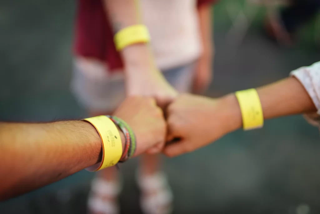 3 hands fist bumping together in yellow wristbands