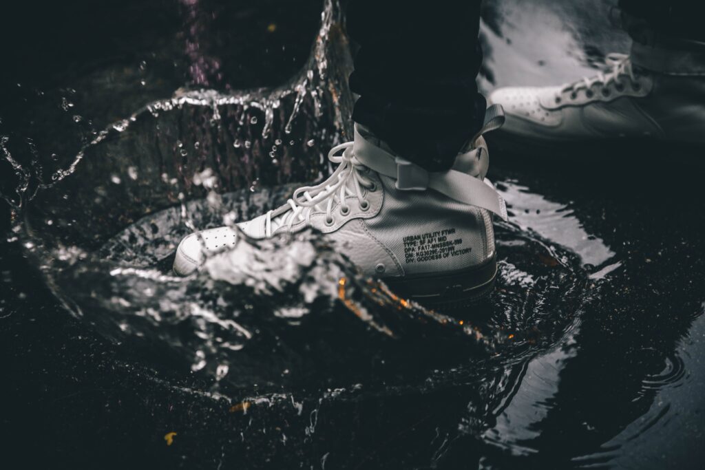 A person wearing white sneakers standing in water