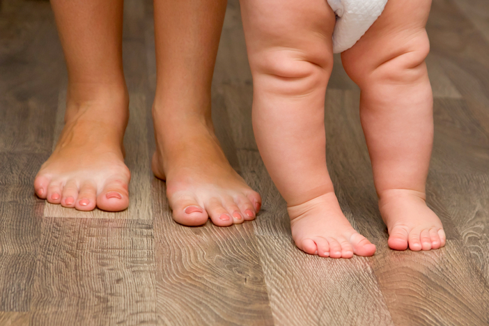 A woman and her baby standing on a wooden floor