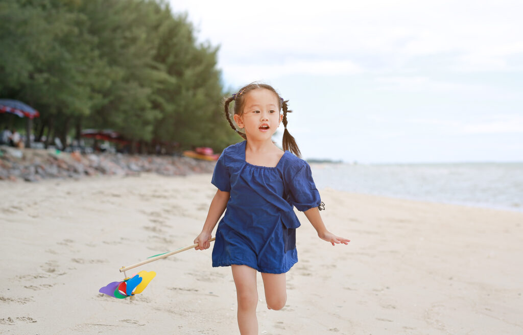 A child running on a beach with a toy