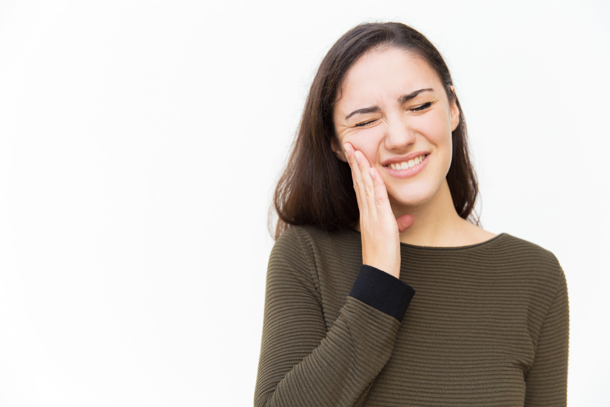 A women placing her hand on her cheek due to jaw pain