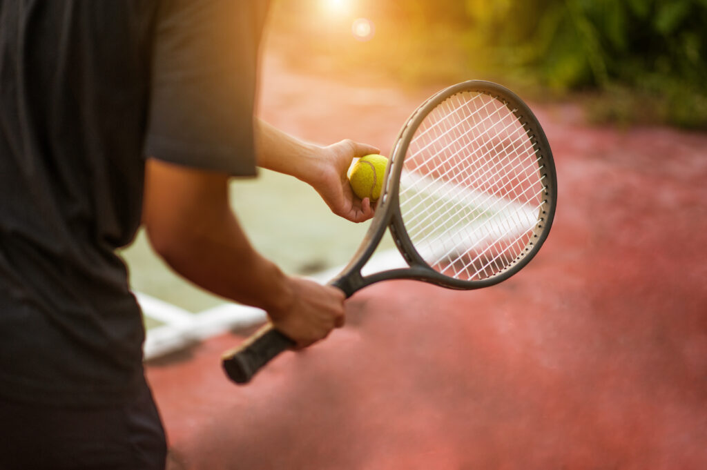 a guy holding a tennis racket and ball