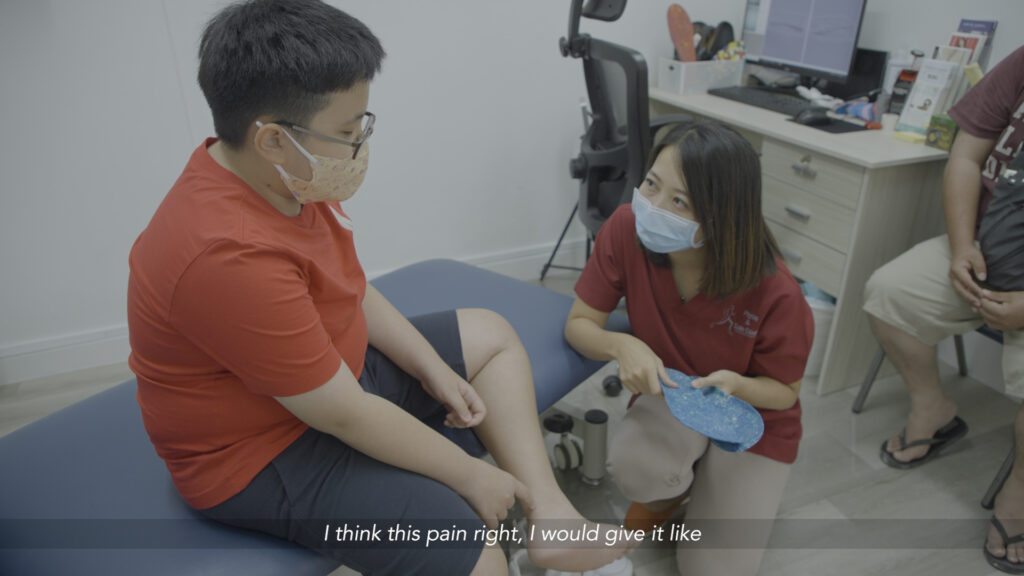 a podiatrist holding onto a pair of insoles while talking to a boy in spectacles