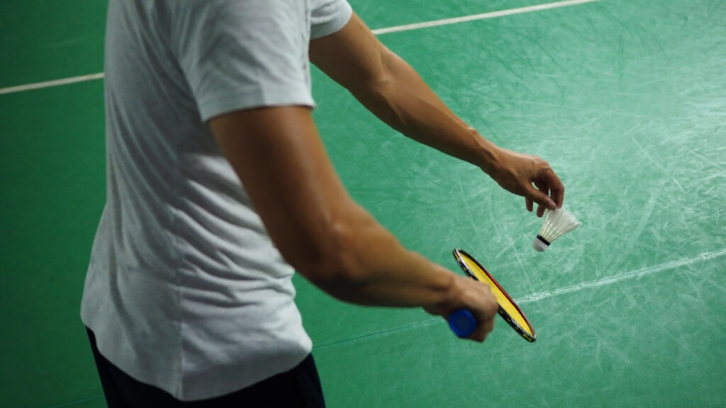 a man about to serve a shuttle cock with his badminton racket