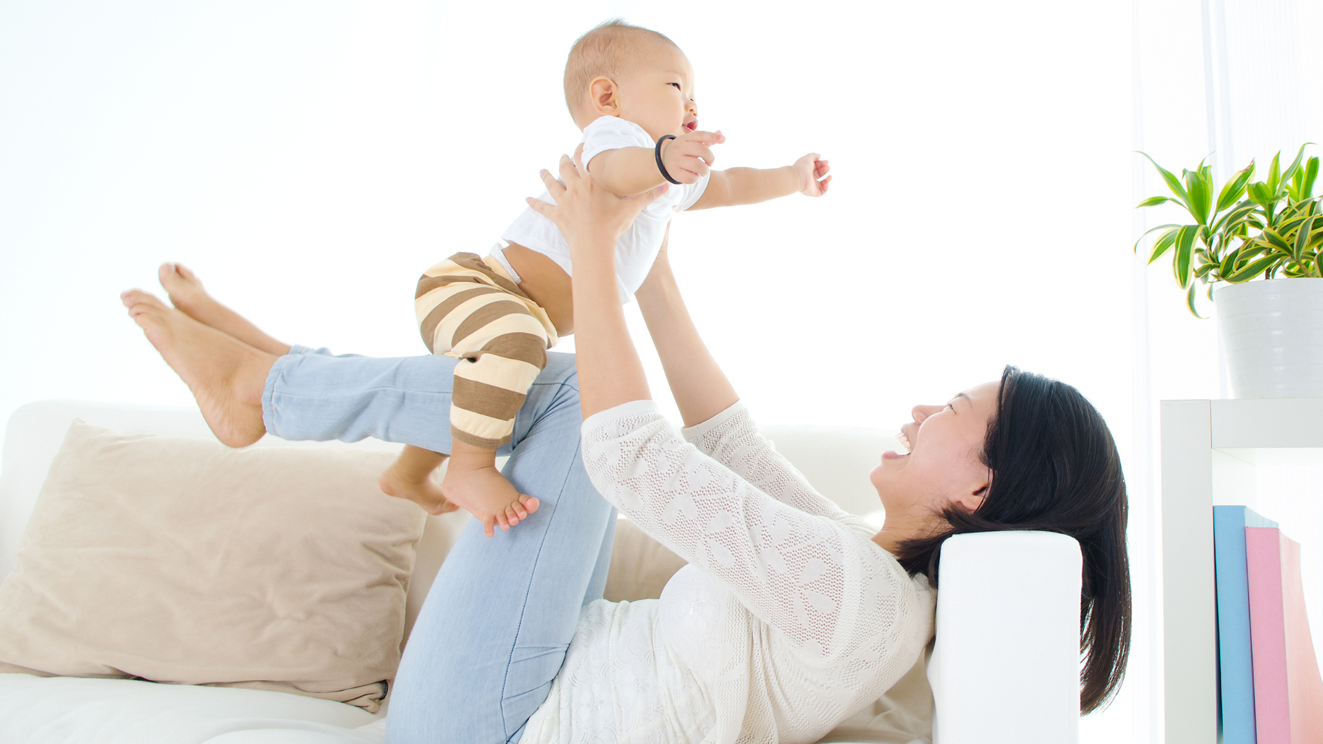 Asian mother playing with baby on couch