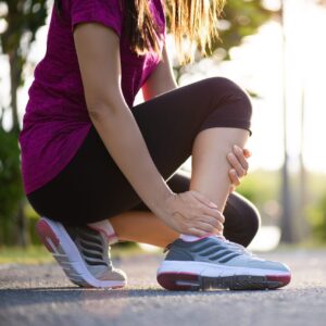 A closeup of a woman suffering from an ankle injury while exercising and running