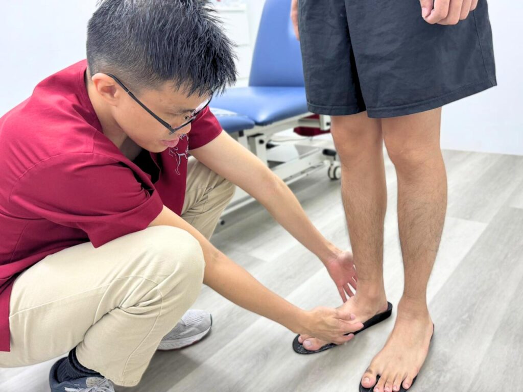 Podiatrist in Singapore assessing a patient's foot alignment for custom orthotic insoles in a clinical setting.