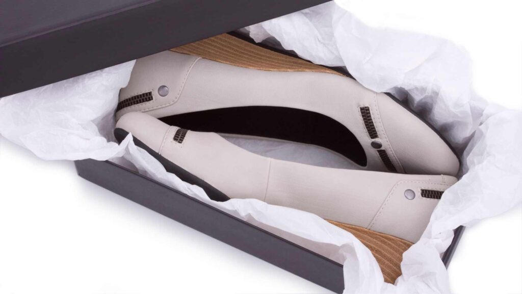 Pair of elegant white shoes in a box with tissue paper, representing new footwear ready for an event.