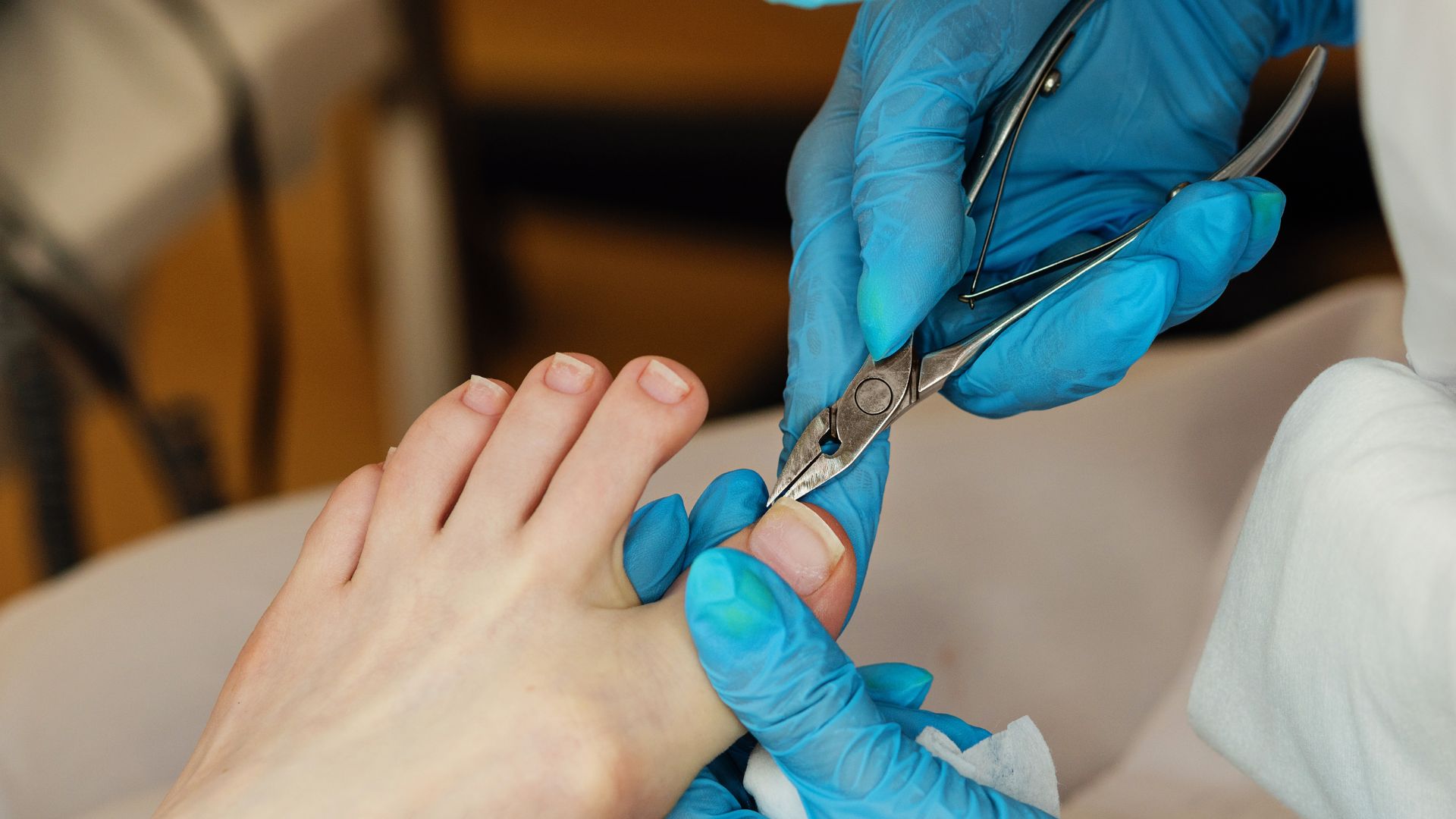 Close-up of a podiatrist performing a medical pedicure, trimming toenails with professional-grade clippers while wearing blue gloves.