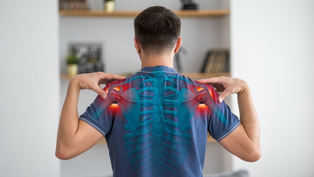 Man holding his shoulders, highlighting areas of shoulder joint pain commonly associated with frozen shoulder (adhesive capsulitis).