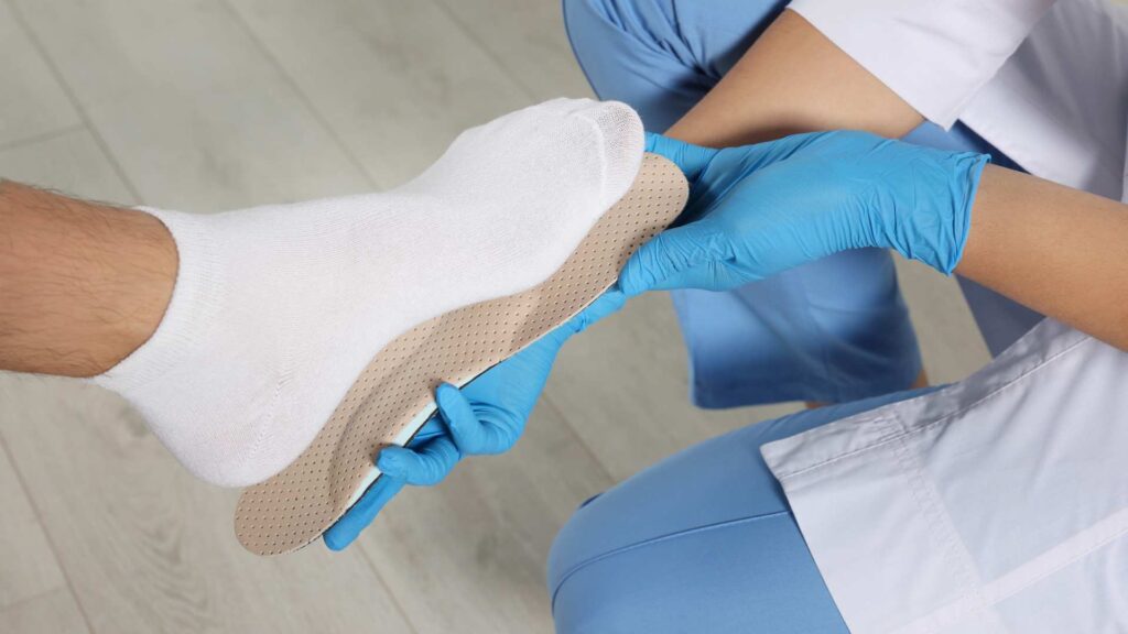 Podiatrist fitting a custom flat feet insole for a patient to provide arch support, improve foot alignment, and relieve pain. Flat feet insoles help enhance comfort and mobility for those with fallen arches.