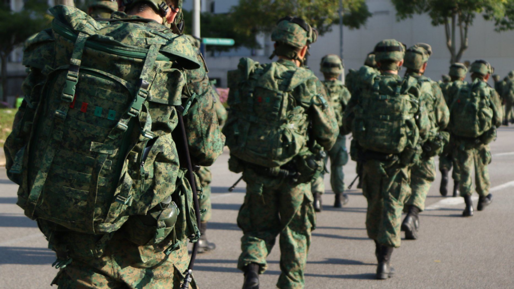 SAF recruits on a route march during BMT training, highlighting the importance of physio advice to reduce back and shoulder strain.