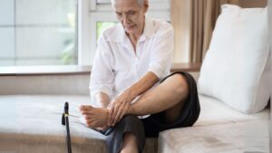 Senior woman massaging her ankle, showing signs of age-related foot pain or stiffness