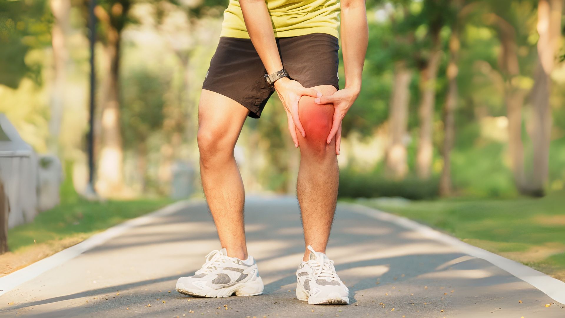 Runner outdoors gripping his inflamed knee, indicating runner’s knee pain.