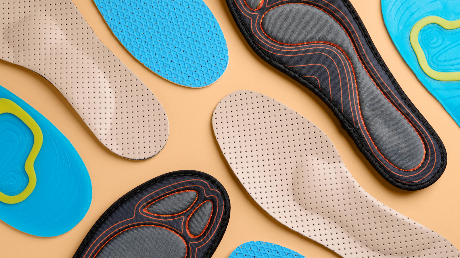 Assorted custom sports insoles in different materials and designs laid out on a flat surface