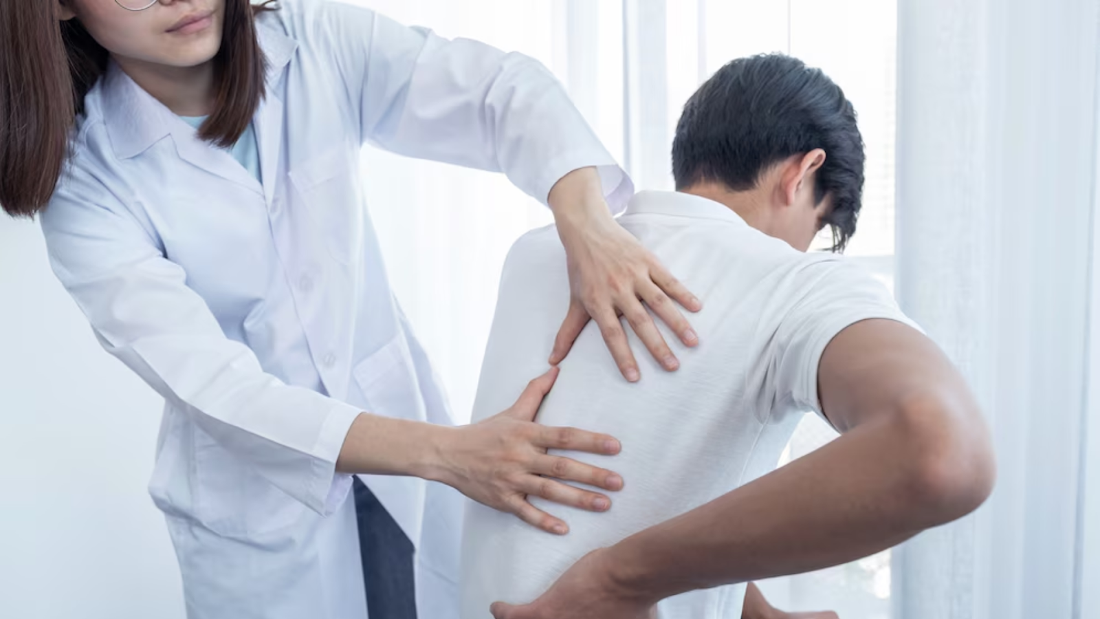  Healthcare professional examining a man’s upper back pain during a consultation