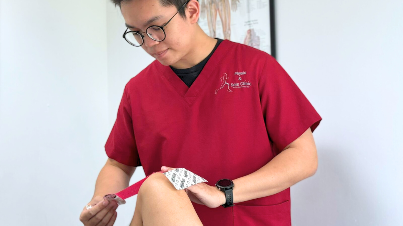 Physiotherapist at Physio & Sole Clinic applying kinesiology tape on a patient’s knee for runner’s knee support.