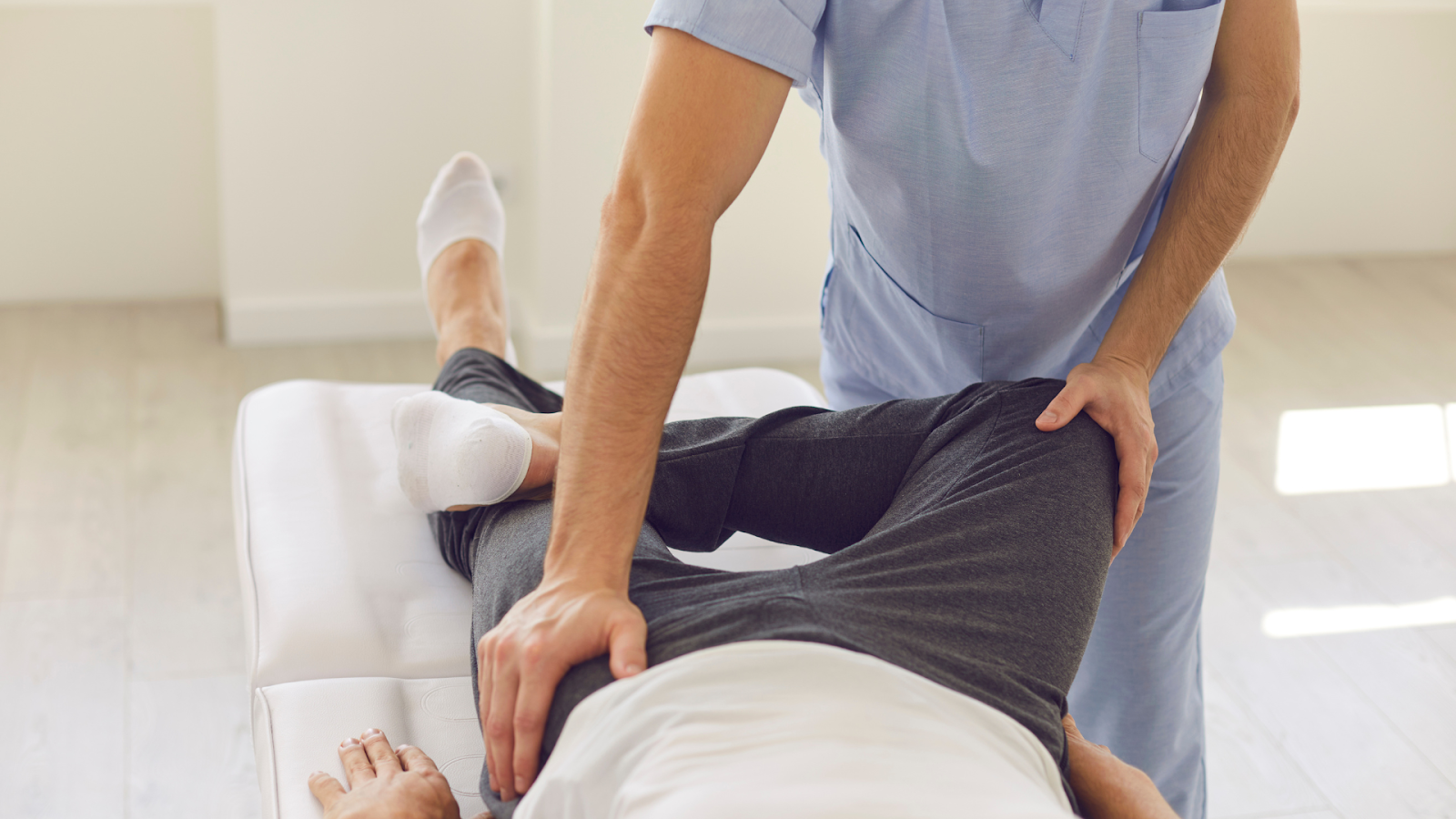 Therapist supporting senior patient’s leg during physiotherapy session for lower limb pain