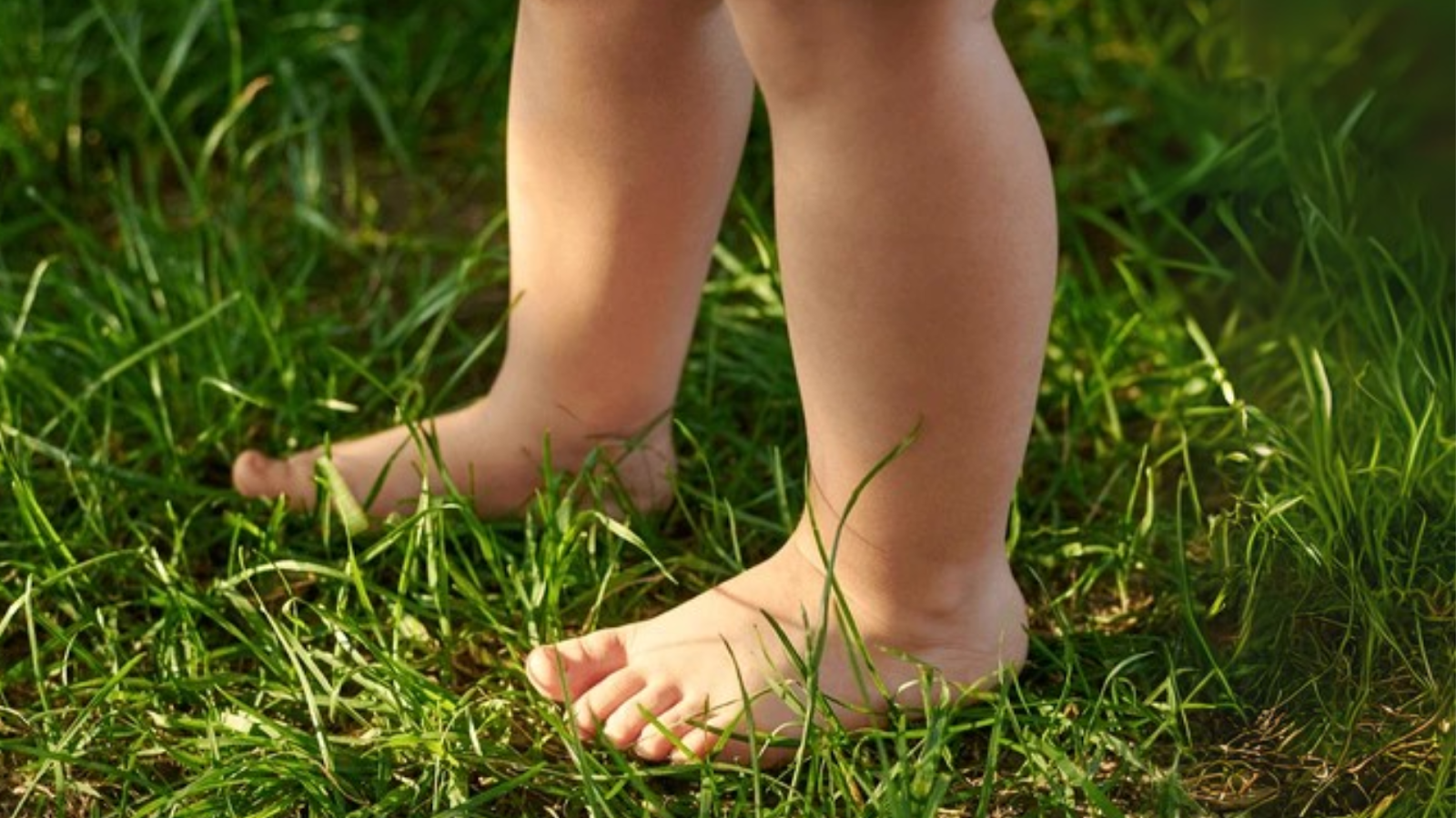 Child standing barefoot on grass, showing natural foot posture.