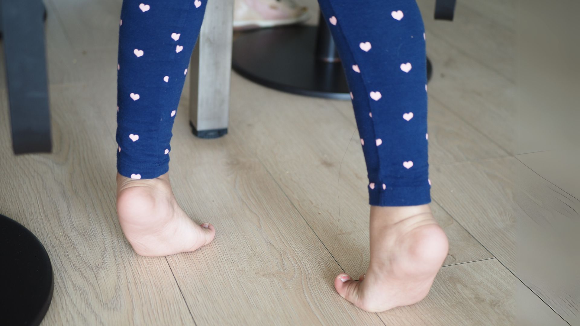 Child wearing blue heart-patterned leggings walking on tiptoes indoors, a common posture seen in toe walking in children in Singapore.