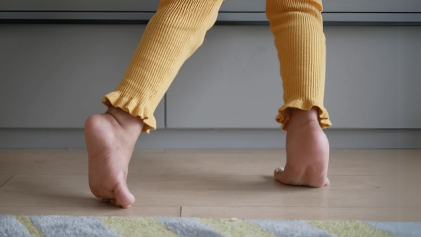 Young child in yellow pants walking on tiptoes at home, showing signs of toe walking in children in Singapore.