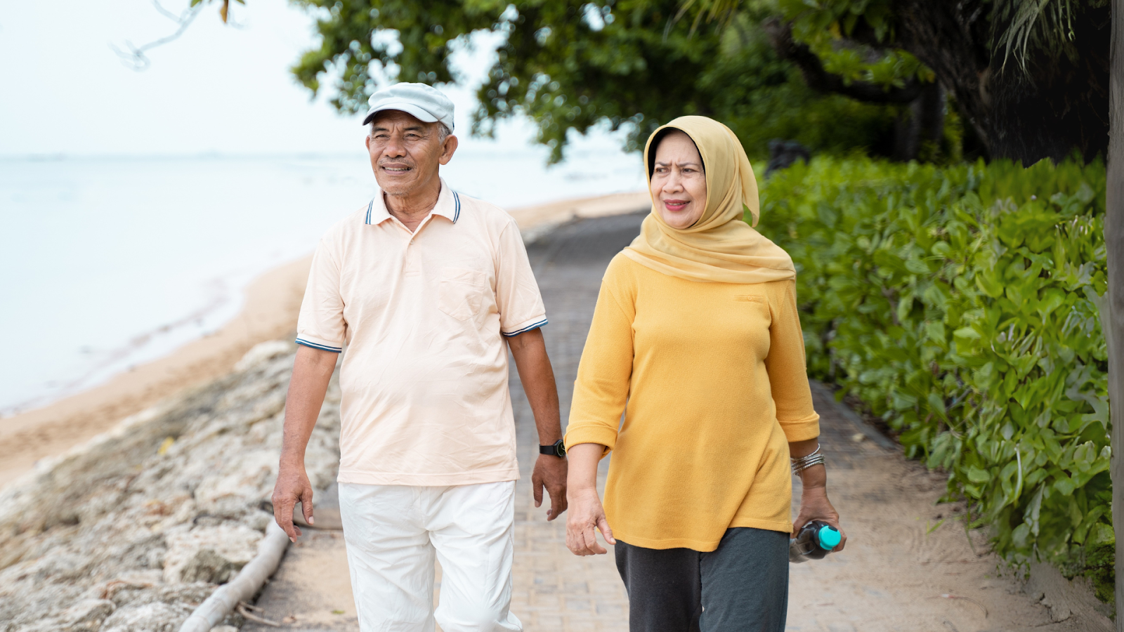 Older couple walking outdoors as part of a supervised physiotherapy routine to manage joint pain.