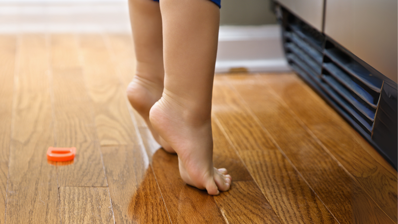 Close-up of child toe walking barefoot on wooden floor, highlighting gait concerns in children in Singapore.