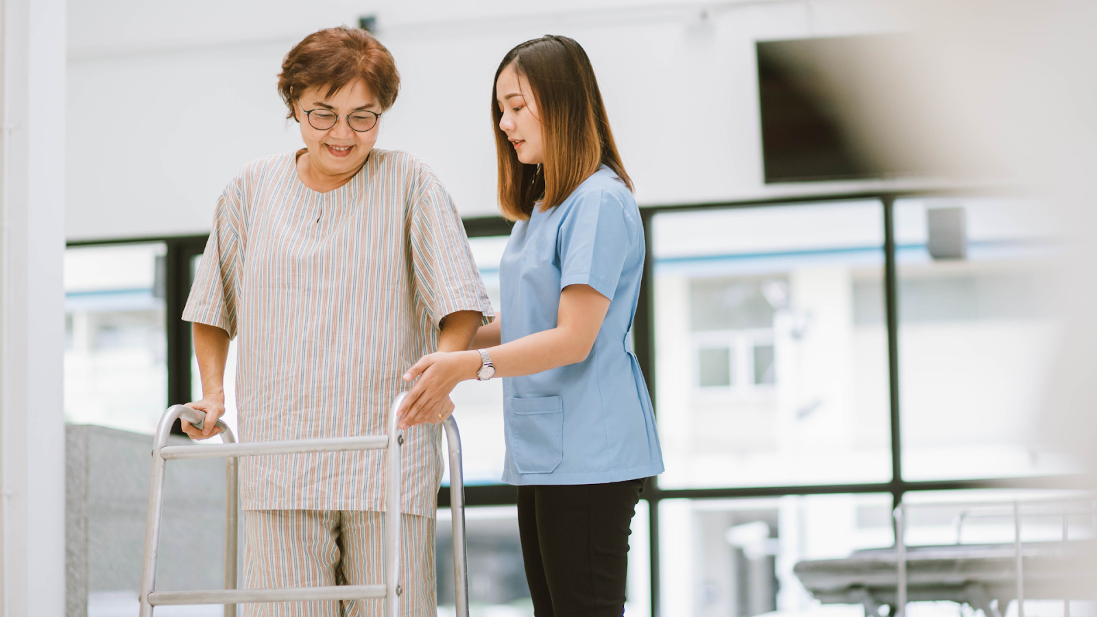  Female physiotherapist guiding older woman through assisted walking as part of post-surgery rehab in Singapore